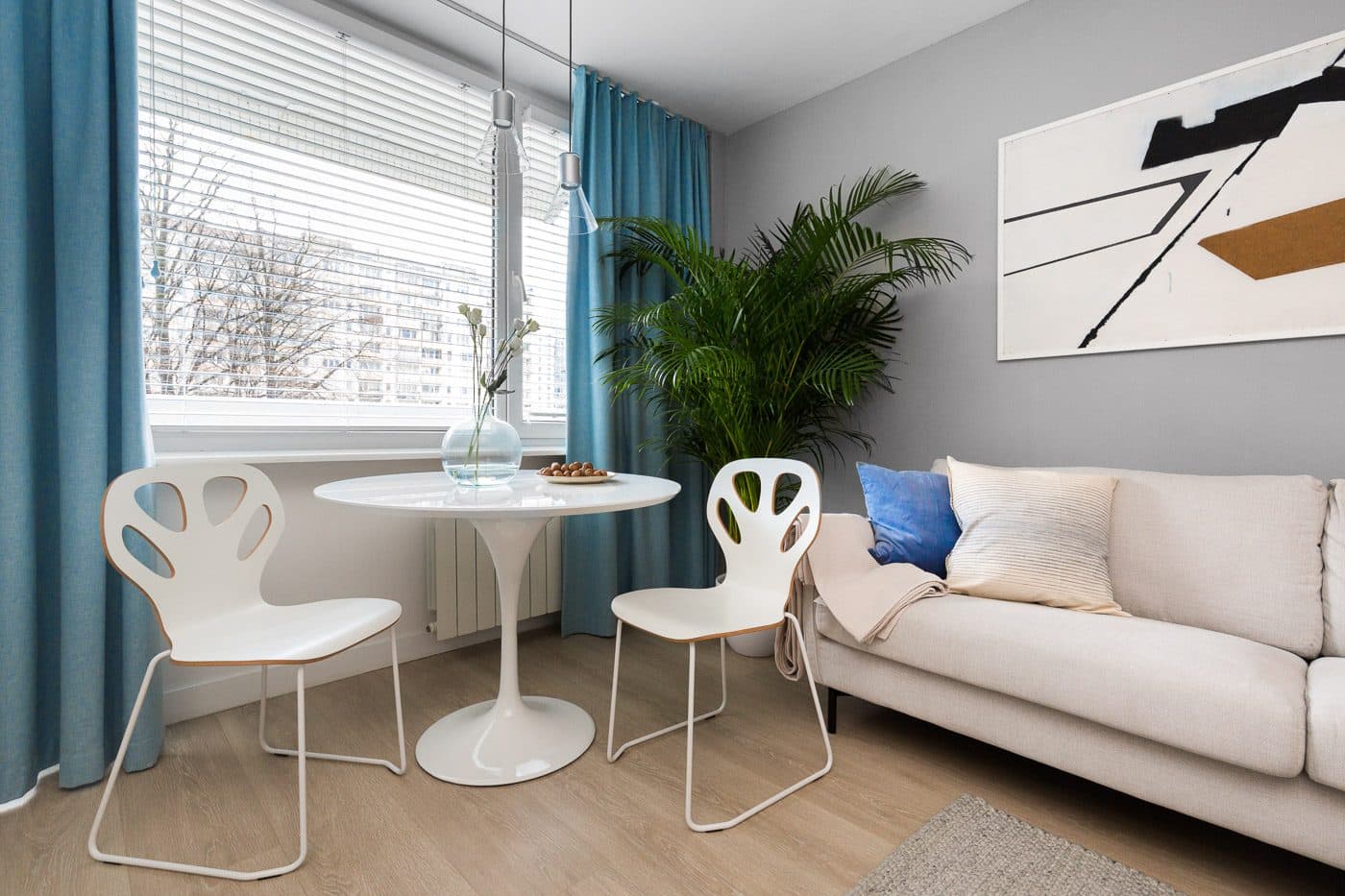 Okrągły stół z dwoma krzesłami przy oknie, obok sofa